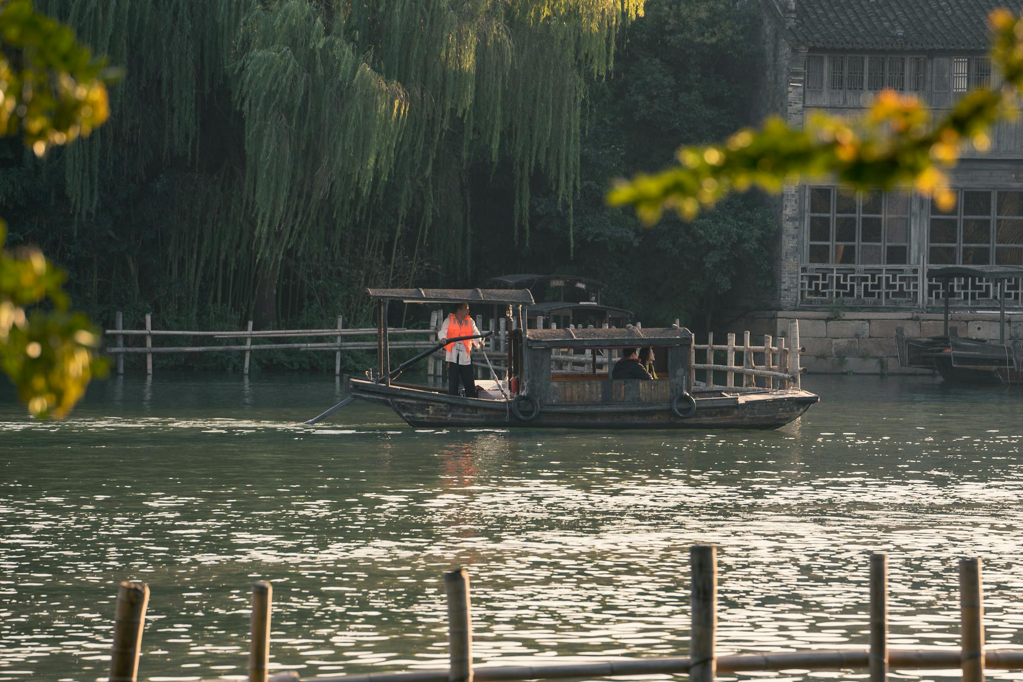 A serene boat ride in Hangzhou's picturesque waters, surrounded by lush greenery.